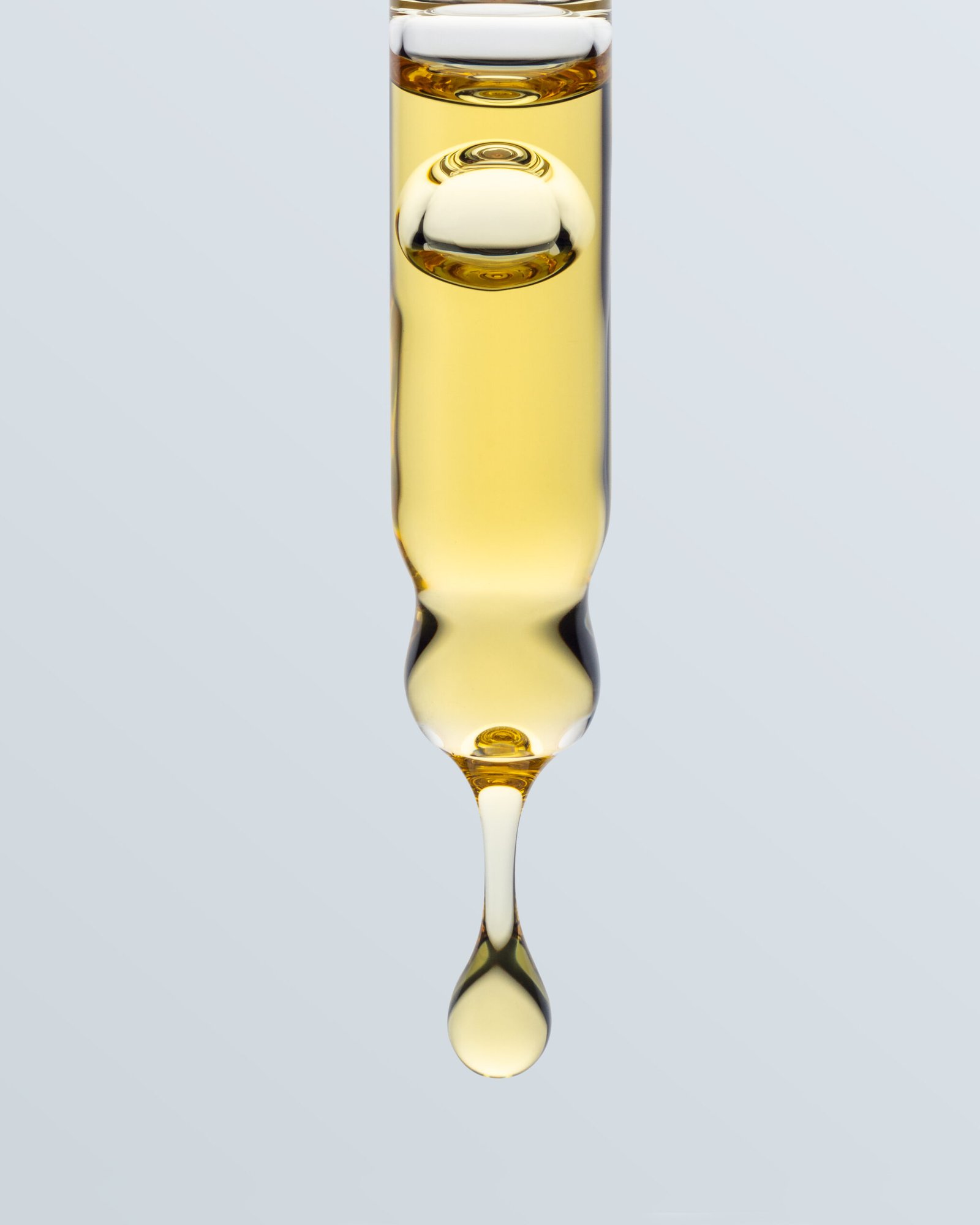 Imagen de un gotero de vidrio con una gota de aceite dorado cayendo, destacando la consistencia y pureza del aceite CBD.