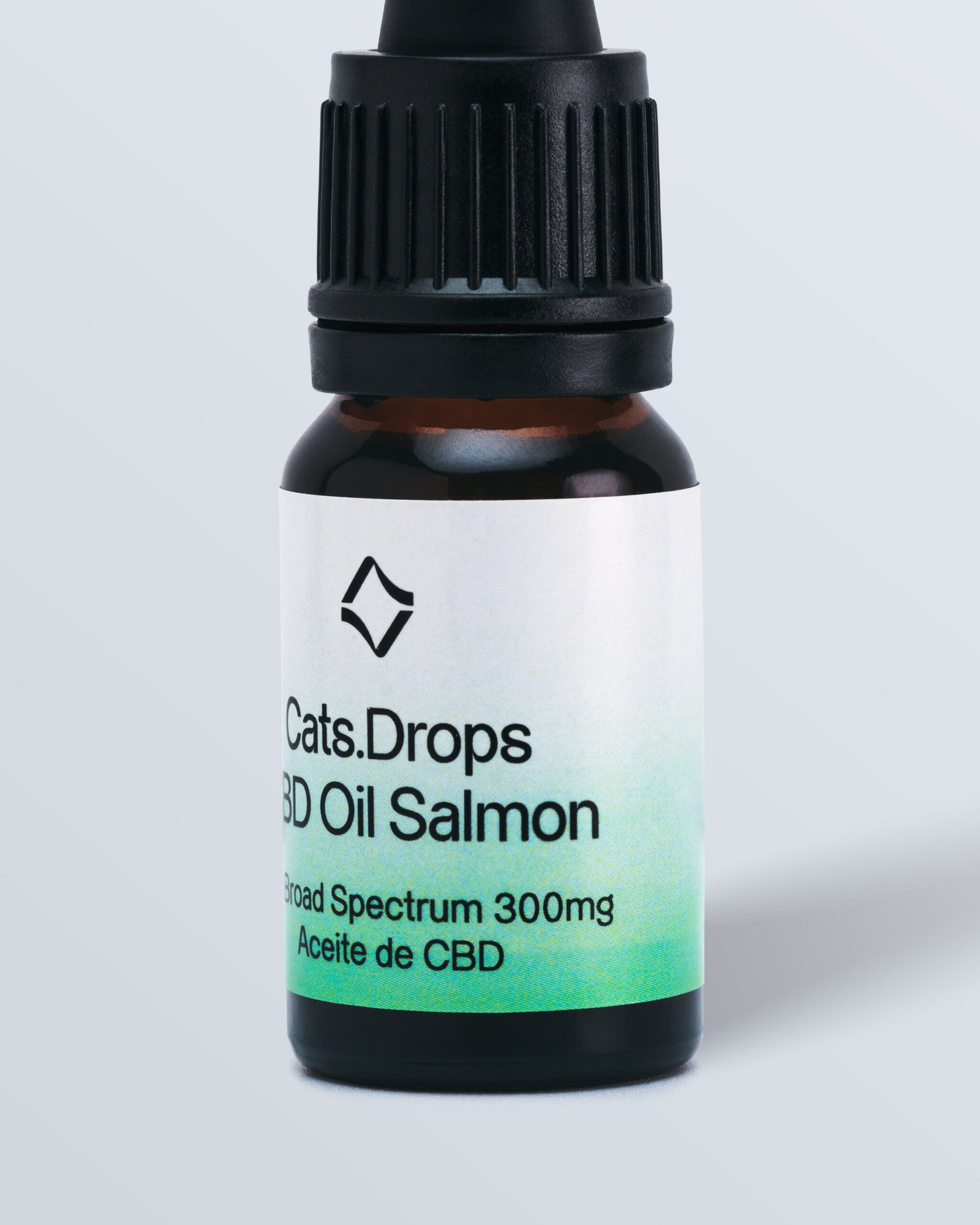 Primer plano de un frasco marrón con una etiqueta blanca y verde 'Cats Drops CBD Oil salmón' con 3000 mg de espectro amplio de CBD.